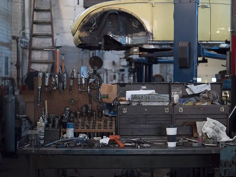 Workbench with toolboxes and air tools beneath a car on a lift